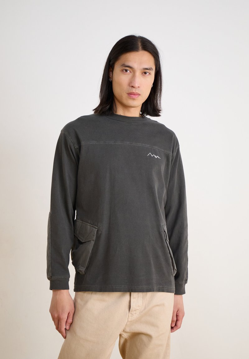 Dark gray long-sleeve shirt with crew neck, featuring a mountain logo, side pockets, and contrasting stitching on the shoulders.