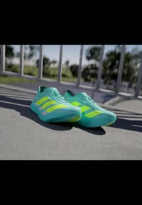 Aqua-green athletic shoes with bright yellow accents, sleek design, smooth texture, laced closure, and three diagonal stripes on each side.