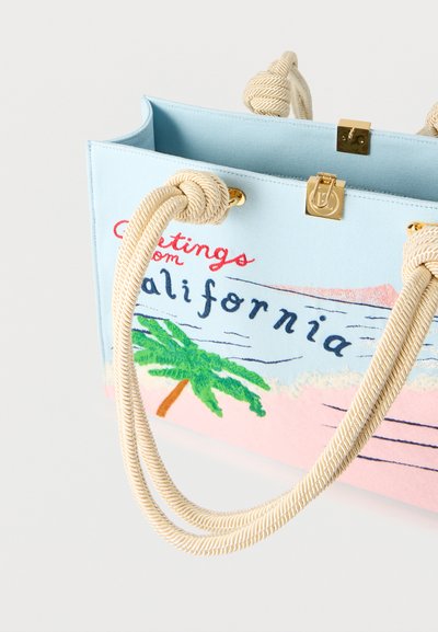 Τσάντα ώμου ανοιχτού γαλάζιου με λαβές από σχοινί, χρυσό κούμπωμα και κεντημένη φράση «Χαιρετίσματα από την Καλιφόρνια» με σχέδιο φοίνικα και ωκεανού.