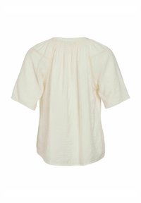 Kortärmad, krämfärgad topp i lätt tyg, med samlad ryggdetalj och subtila texturerade accenter.
