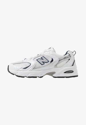 Witte sport schoen met mesh bovenkant, marineblauwe accenten en een gehoorzaamde zool. Bevat het "N" logo, veters en een gestructureerde detail aan de zijkant.