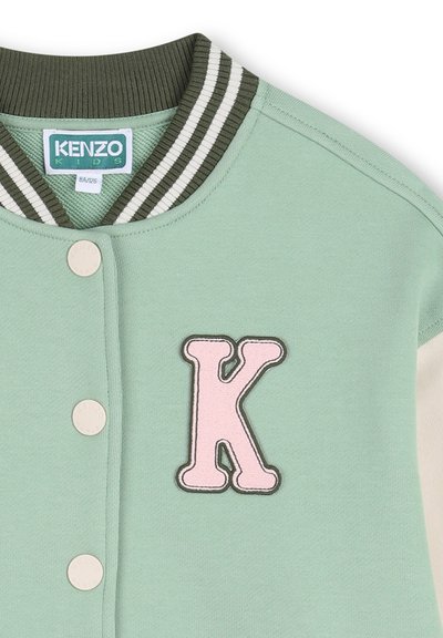 Sweat-shirt vert avec col côtelé rayé ; présente une lettre "K" rose brodée et des boutons-pression. Matière douce en mélange de coton.