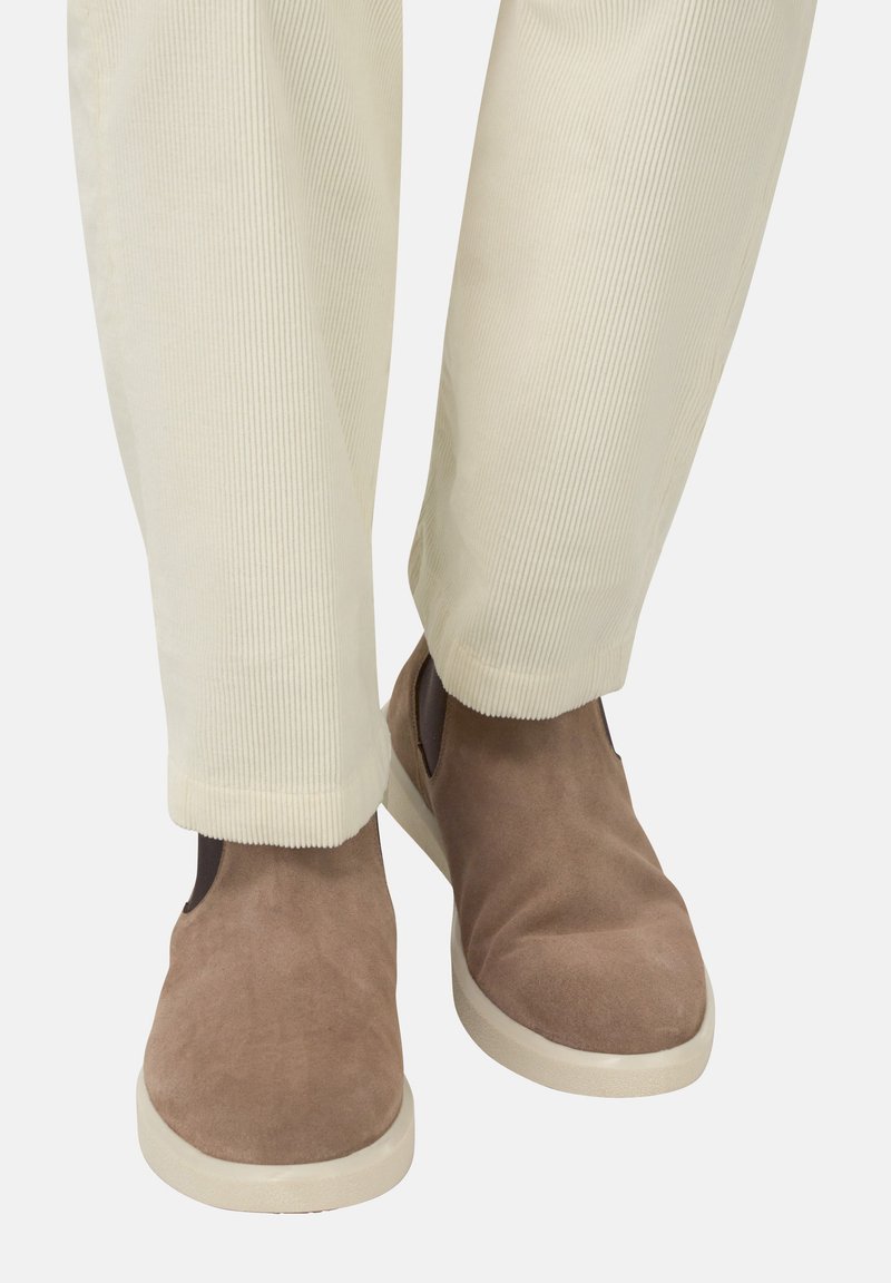 Hnedé semišové nazúvacie topánky s jemnou textúrou, skombinované s krémovými rebrovanými nohavicami, ktoré sa mierne zúžia pri členku.