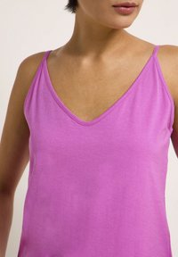 Lila linne med tunna axelband, v-ringning, tillverkat av mjukt, slätt tyg, med en enkel, oförziad utseende.