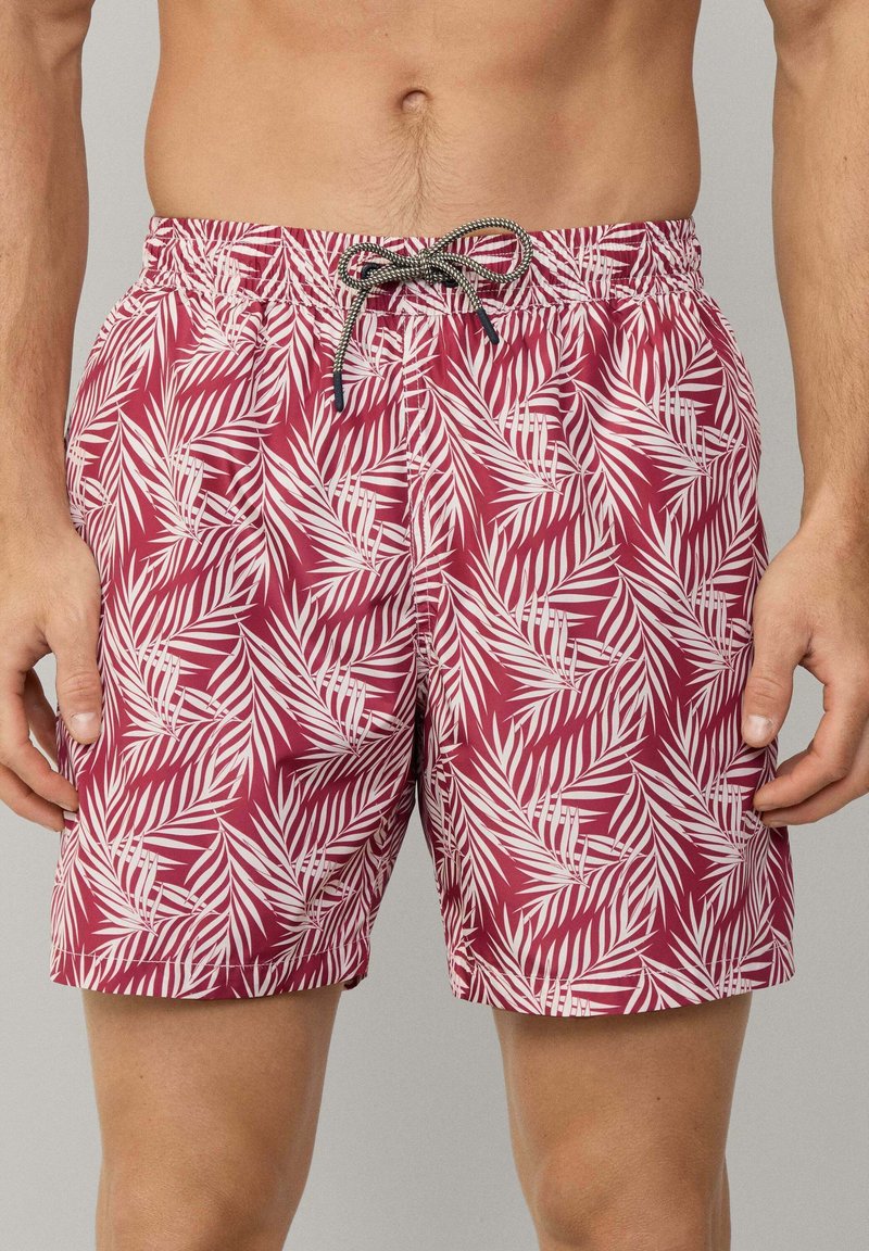 Pantaloni da bagno bordeaux con un motivo di foglie di palma bianche, fascia elastica in vita e chiusura con cordino. Tessuto leggero con una superficie liscia.
