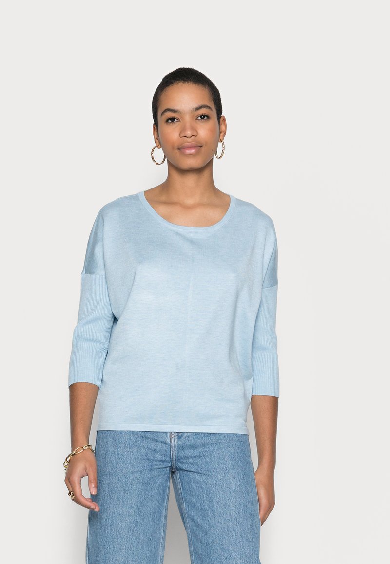 Lys blå, ribbet striktrøje med rund hals og trekvartærmer, parret med lys blå denim jeans.