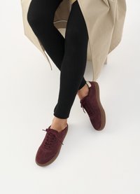 Burgundi suede tossud kummiga, millel on nöörimine, ümar nina ja kontrastne kannatõmme. Kandmiseks mustade soonikute retuusidega.