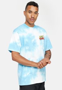 Modrá tričko s vázaným vzorem a volným střihem. Obsahuje vytištěné logo "Street Fighter" na hrudi a krátké rukávy. Měkká bavlněná tkanina.