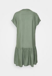 Vestido verde oliva de corte relajado, con mangas cortas y un dobladillo de volantes en capas. Fabricado con una tela suave y de textura lisa.