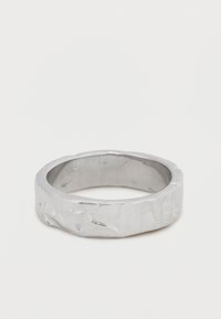 Ασημένιο δαχτυλίδι με υφή και άνιση επιφάνεια και λεία εσωτερική μπάντα. Το φαρδύ, στρογγυλεμένο σχήμα τονίζει τον στιβαρό και μινιμαλιστικό του σχεδιασμό.
