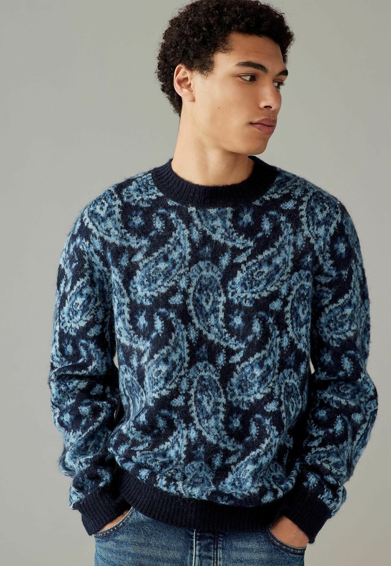 Navyblauer Pullover mit Paisleymuster in verschiedenen Blautönen, gerippter Rundhalsausschnitt und -manschetten, aus weichem, strukturiertem Strickstoff.