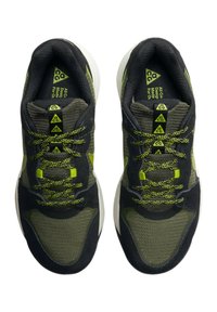 Svarta och gröna träningsskor med överdel i mesh och mocka, texturerade snören, triangulärt varumärke och en vit gummisula.
