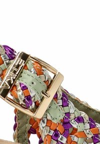 Las sandalias trenzadas cuentan con correas multicolores en verde, naranja, púrpura y metálico, con un acento de hebilla dorada. Diseño texturizado y con patrones.