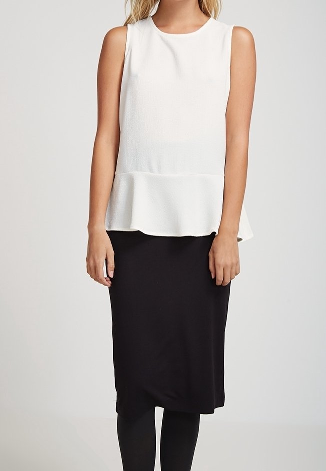 Top blanco sin mangas con peplum y tela texturizada, combinado con una falda negra ajustada, creando un conjunto bicolor y contrastante.