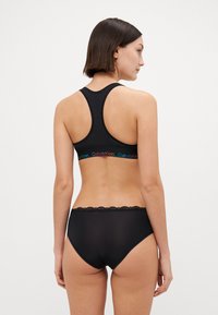 Svart bomullssportbh med racerbackdesign, med en färgglad Calvin Klein-logoband. Matchande hög midja underkläder med spetsdetaljer.