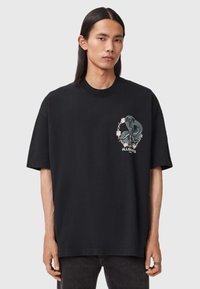 Μαύρη κοντομάνικη μπλούζα φτιαγμένη από βαμβάκι, με κεντημένο σχέδιο φιδιού και λουλούδια στην αριστερή πλευρά του στήθους.