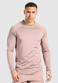 Langarm-Athletikshirt aus weichem, staubrosa Stoff, mit rundem Ausschnitt, Raglanärmeln und glatter Textur.