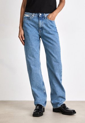 Jeans dritti blu chiaro in tessuto denim, con un classico design a cinque tasche e chiusura con bottone in metallo, abbinati a mocassini neri.