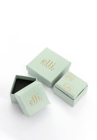Grønne papir smykkeblikke med guld branding, der har en kvadratisk og en sekskantet form, hvoraf den ene er åben og afslører et sort indre.