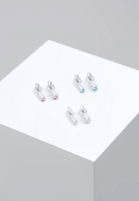 Pendientes de plata con tachuelas que presentan cristales de colores: dos rosas, uno azul y uno transparente. Cada uno tiene un diseño redondeado sencillo y un cierre a presión.