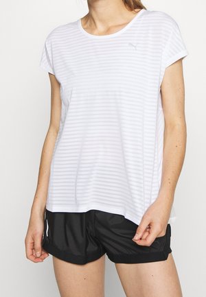 Vrouw draagt een witte gestreepte sporttop met korte mouwen en zwarte hardloopshorts met een klein reflecterend logo aan de zijkant.