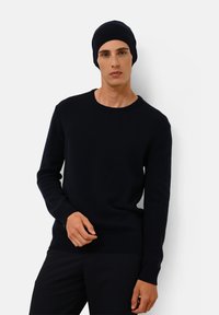 Marineblauwe gebreide trui met een ronde hals en lange mouwen, gecombineerd met een bijpassende beanie. Glad textuur, slim fit ontwerp.