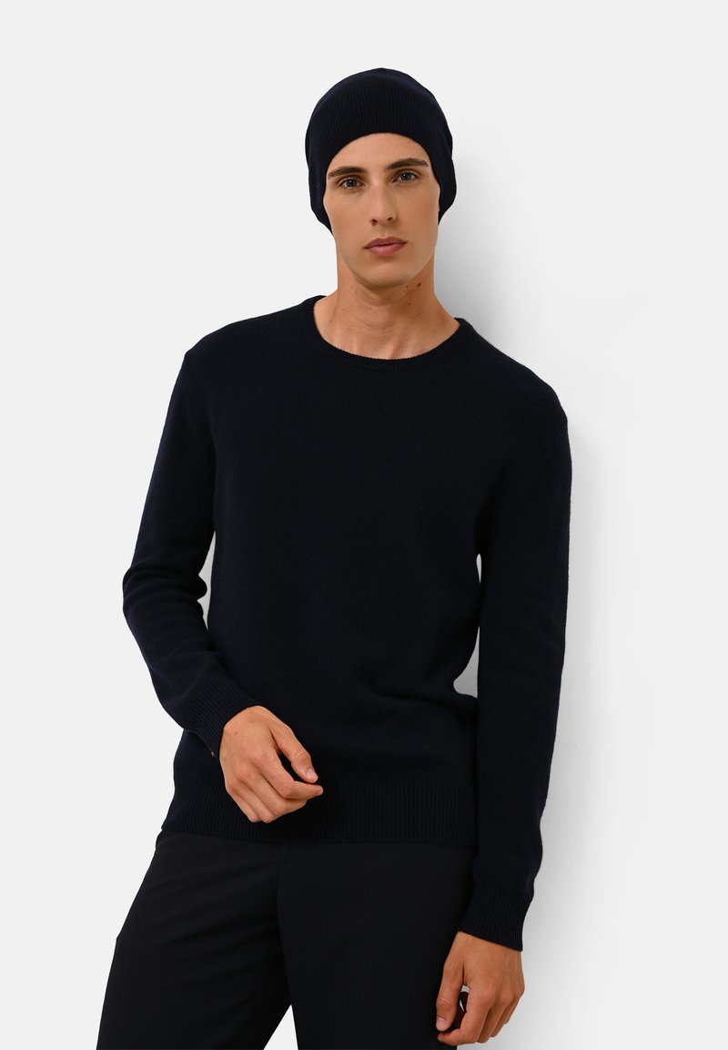 Marineblauwe gebreide trui met een ronde hals en lange mouwen, gecombineerd met een bijpassende beanie. Glad textuur, slim fit ontwerp.