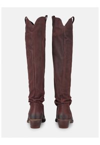 Botas de cuero marrón hasta la rodilla con un borde superior ondulado, punta redondeada y tacón apilado, que cuentan con una textura suave y un diseño ajustado.