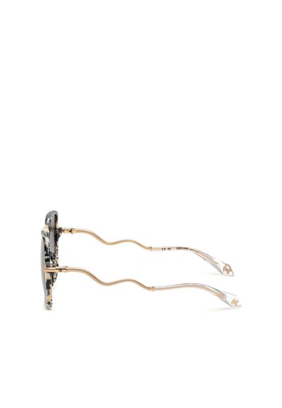 Vue latérale de lunettes de soleil avec une monture marbrée noire et beige, des branches texturées dorées et des embouts de branches transparents incurvés avec des accents dorés.