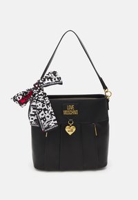 Bolso de mano de cuero negro con diseño plisado, herrajes dorados y un pañuelo decorativo con patrones de texto. Adornado con un charm en forma de corazón.