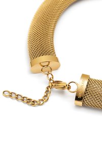 Goldfarbener Mesh-Choker mit zylindrischen Enden, glänzender Oberfläche und Kettenverbinder. Eingravierte Markenbezeichnung auf einem Ende sichtbar.