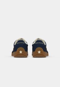 Marineblå ruskinds sneakers med gummisål, prydet med hvide detaljer og en stjernesymbol på hælen. Logoet er synligt på bagsiden.