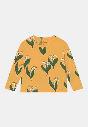 Chemise enfant jaune à manches longues avec un motif de muguet vert et blanc et un col rond.