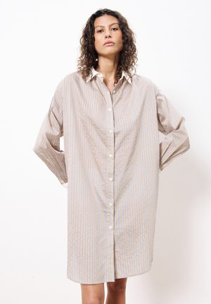 Robe chemise à boutons dans un tissu léger, présentant des rayures verticales beiges et bleues, avec un col classique et de longues manches amples.
