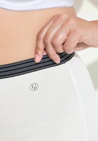 Witte hoge taille leggings met een zwart en grijs gestreepte elastische tailleband en een ronde logo op de stof gedrukt.