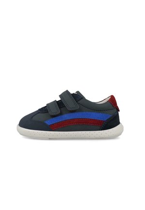 Zapatilla deportiva azul marino para niños con rayas laterales rojas y azules, dos tiras ajustables de velcro y suela blanca perforada.