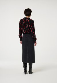 Black blouse with red chili pepper print; paired with a long, dark denim skirt. The look is complemented by knee-high black boots.