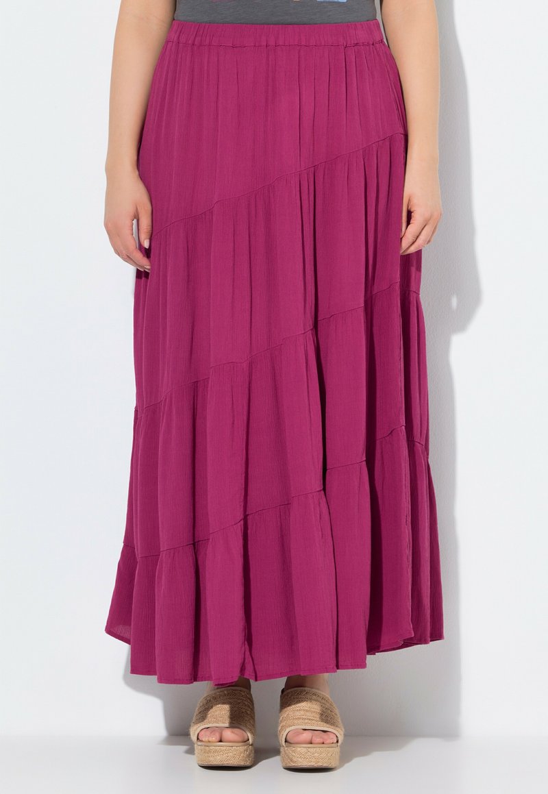 Lange, gestufte Rock in lebhaftem Magenta, mit horizontalen Falten und einem elastischen Bund. Tragen mit beigen Keilsandaletten.