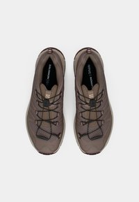 Καφέ αθλητικά παπούτσια με πλέγμα στο πάνω μέρος, μαύρα κορδόνια και μαλακή σόλα. Διαθέτουν υφή σχεδίασης και λογότυπο στην ταμπέλα της φτέρνας.