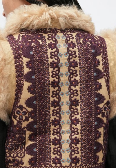 Υφασμάτινο γιλέκο με περίτεχνη κεντητική σε αποχρώσεις του μοβ και του μπλε σε μπεζ φόντο, με αφράτο γιακά και λεπτομερή λουλουδένια σχέδια.