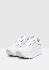 Sneakers bianchi con pannelli in rete, punta rotonda, occhielli argentati e accenti metallici. Suola rialzata con un motivo di battistrada testurizzato.