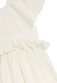 Abito bianco di cotone con scollatura e orlo arricciati, maniche corte e un tessuto testurizzato, che enfatizza la morbidezza e il design leggero.