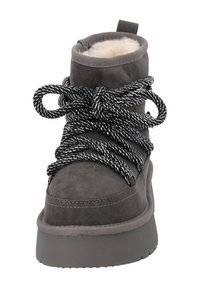 Stivaletto alla caviglia grigio in suede con fodera morbida, suola spessa grigia e lacci a pattern bianco e nero. Presenta un tirante sul retro.