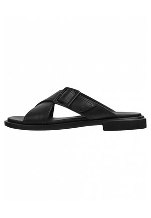 Zwarte leren slippers met gekruiste bandjes en een zijgesp op een platte zool, getoond vanaf de buitenkant.