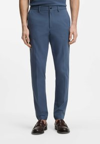 Niebieskie spodnie wizytowe o gładkiej fakturze, lekko zwę�żanym kroju, z szlufkami na pasek i gładkim przodem. Stylizowane z brązowymi mokasynami.