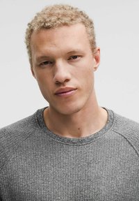 Pelēks teksturēts džemperis ar apaļu kakla izgriezumu un raglanu piedurknēm. Materiāls ar nedaudz paaugstinātu rakstu. cieši pieguļ ap kaklu.