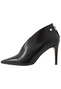 Chaussure à talon haut en cuir noir avec bout pointu, texture lisse et détail de fermeture  éclair à la cheville. Le design à talon aiguille accentue la hauteur.