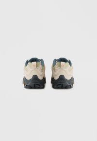 Beige and green textured athletic shoes with a black outsole, featuring a padded collar and branded tabs on the heel.
