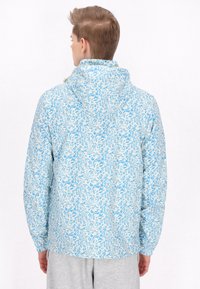 Windbreaker jack met bloemenpatroon in een lichtblauw-witte kleurencombinatie, met capuchon en elastische manchetten. Soepele textuur en casual pasvorm.