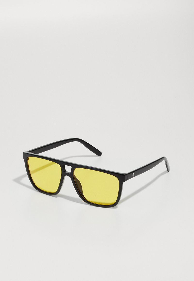 Ochelari de soare negri cu lentile galbene, ramă rectangulară sleek, brațe subțiri și detalii distincte pe partea din față.